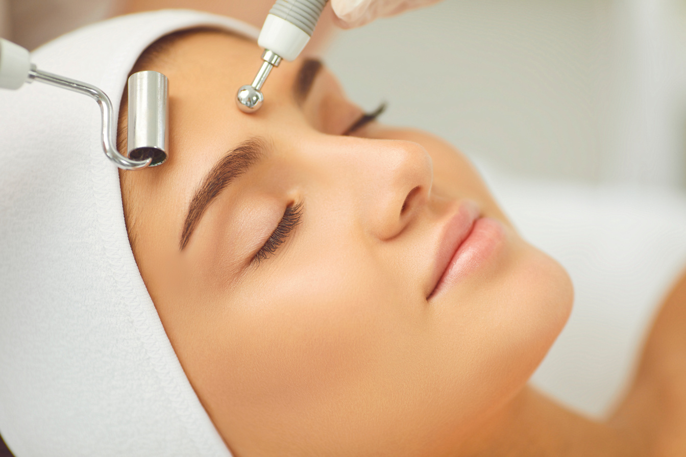 Woman Receiving Facial Microcurrent Treatment from Therapist in Beauty Wellness Salon